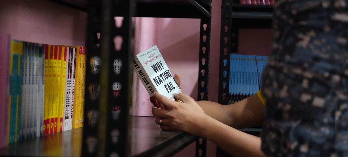 A jail officer reads a book in the library stacks.