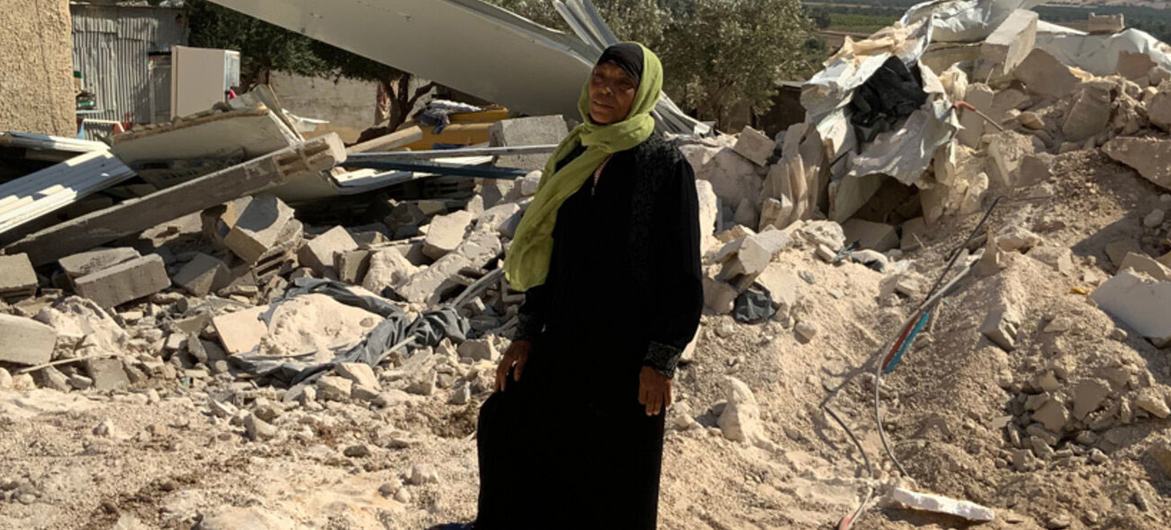 امرأة فلسطينية تقف في حقل من الأنقاض والحطام في منطقة نزاع.