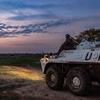 Um soldado de manutenção da paz com capacete azul está sentado em cima de um veículo blindado de transporte de pessoal da ONU durante uma patrulha noturna ao entardecer no Sudão do Sul.
