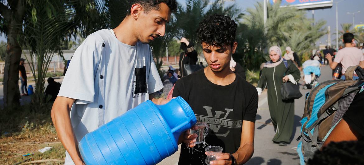 Dos hombres comparten agua potable en la Franja de Gaza.
