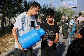 Dos hombres comparten agua potable en la Franja de Gaza.