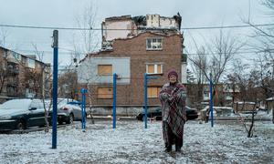 A woman stands outside her bomb-damaged home in Kharkiv, Ukraine.