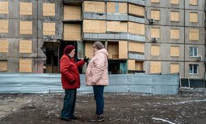 Two women stand in front of their damaged home in Kharkiv, Ukraine.