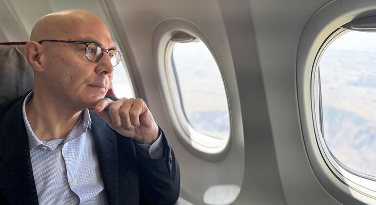 沃尔克·图尔克坐在飞机窗口旁边, 仔细观察下面的景观,