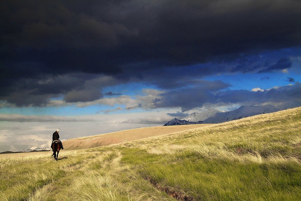 在吉尔吉斯斯坦，一位骑马者朝着山脉前行。