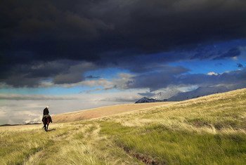 A horse rider heads towards mountains in Kyrgyzstan .