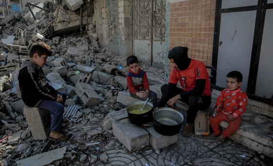 رجل فلسطيني يطهو لأطفاله أمام منزلهم المدمر في حي الرمال، غرب مدينة غزة.