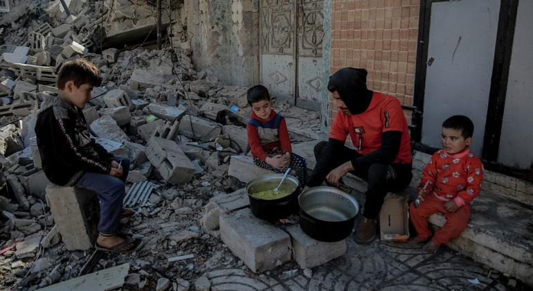 A man cooks food for his children over a wood fire in front of his destroyed home in al-Rimal neighuborhood, west of Gaza City.