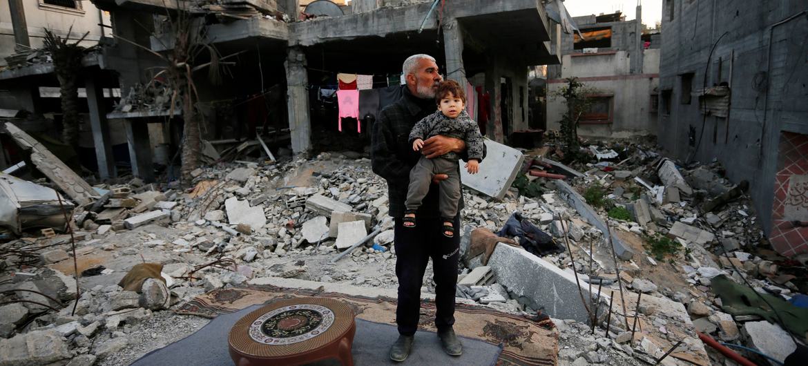 Un hombre con un niño entre los restos de casas destruídas en la Franja de Gaza