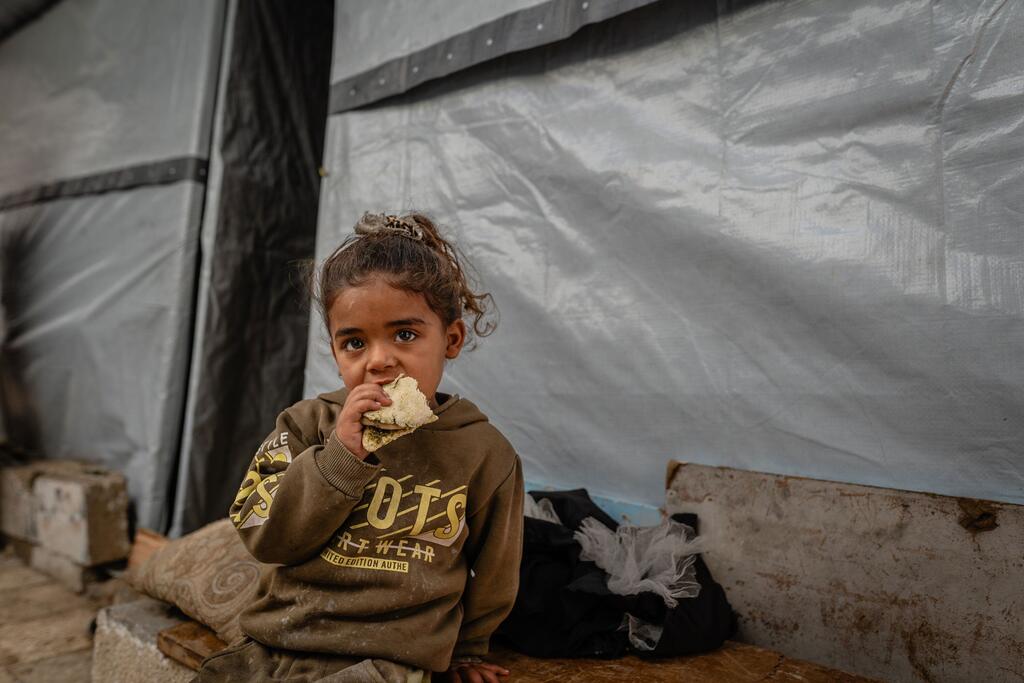 فتاة فلسطينية صغيرة في غزة تأكل قطعة خبز.