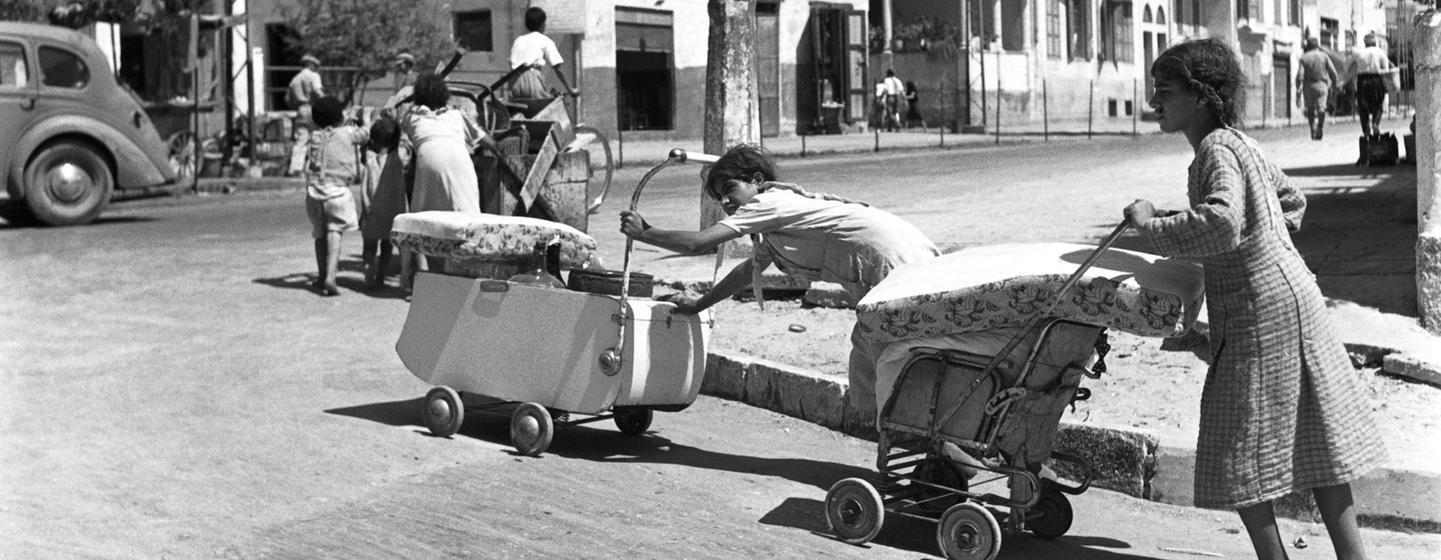 Pieds nus et poussant leurs affaires dans des landaus et des charrettes, des familles arabes quittent la ville côtière de Jaffa, qui fait désormais partie de l'agglomération de Tel-Aviv, dans l'État d'Israël.