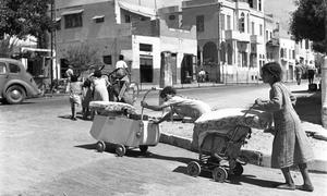 Barefoot and pushing their belongings in prams and carts, Arab families leave  the coastal town of Jaffa which became part of the greater Tel Aviv area in the state of Israel.