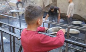 Un niño espera a que le den comida en una cocina comunitaria en Gaza.