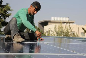 Un ouvrier installe un panneau solaire en Jordanie.