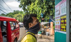 مواطن أندونيسي يقرأ معلومات الوقاية من كوفيد -19 في جاكرتا.