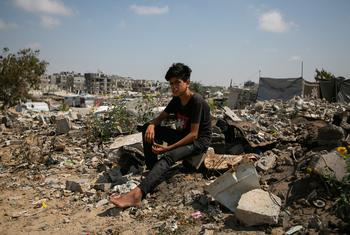 A young man sits atop the rubble of a home in Gaza. Basic services including healthcare and clean water are increasingly difficult to provide, say UN aid agencies.