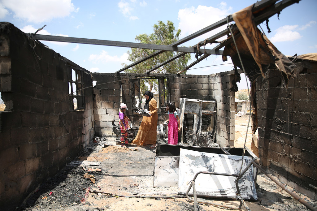 2025年7月，西岸希伯伦南部，一位母亲和她的孩子们在定居者袭击烧毁家中一间房屋后，整理留下的物品。