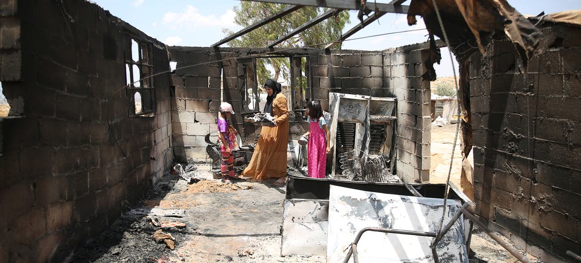 A mother and her children go through their belongings after a room in their home was burned in a settler attack in southern Hebron, West Bank. (July 2025)