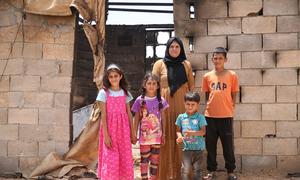 A Palestinian family stands outside their home in southern Hebron, in the West Bank, that was burned in a settler attack.