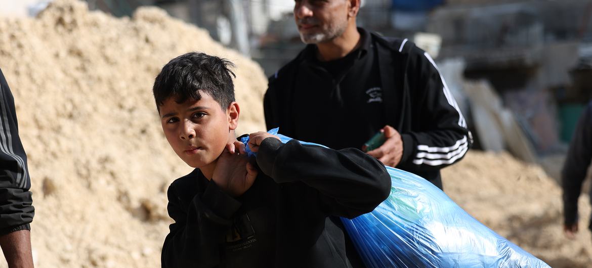 A boy carries possessions as his family leaves their home in Nur Shams refugee camp in the northern West Bank.