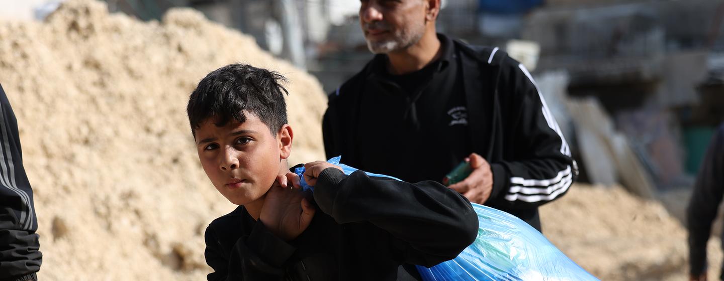 A boy carries possessions as his family leaves their home in Nur Shams refugee camp in the northern West Bank.