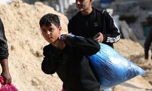 A boy carries possessions as his family leaves their home in Nur Shams refugee camp in the northern West Bank.