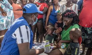 A UN staff member provides medical care to a displaced woman and children.