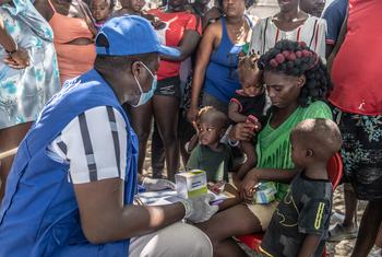 A UN staff member provides medical care to a displaced woman and children.