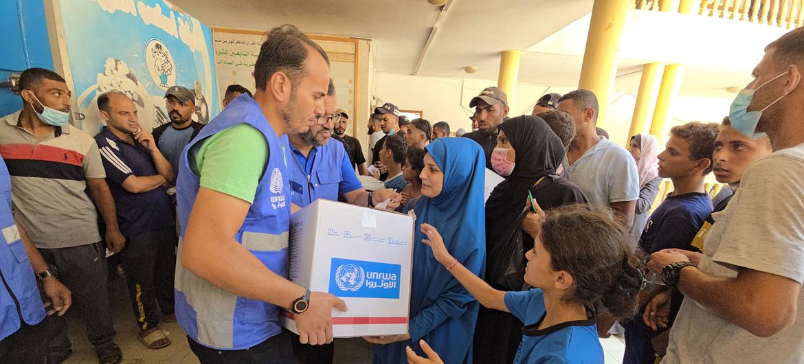 An UNRWA staff member distributing aid to affected civilians in Gaza.