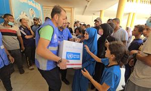 An UNRWA staff member distributing aid to affected civilians in Gaza.