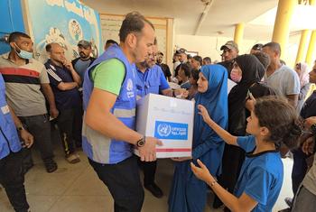 An UNRWA staff member distributing aid to affected civilians in Gaza.