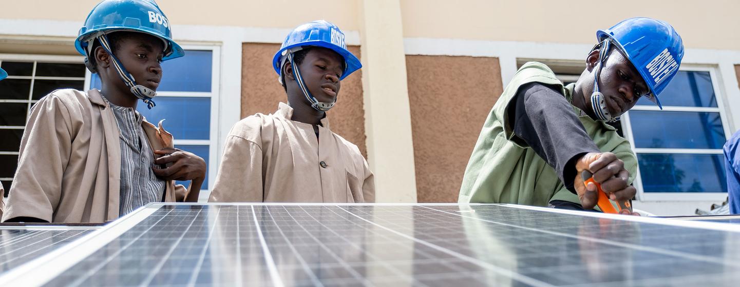 Des hommes installent des panneaux solaires dans l'État du Borno, au Nigeria.