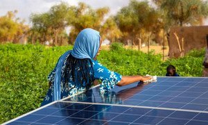 A woman cleans a solar panel in Mauritania.