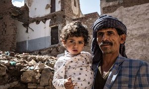 Un père avec sa fille devant un bâtiment détruit à Sana'a, au Yémen.