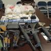 Una colección de armas y municiones ilegales incautadas colocadas en una mesa, incluyendo rifles de asalto, pistolas y cajas de municiones, en el contexto de la violencia de pandillas en Haití.
