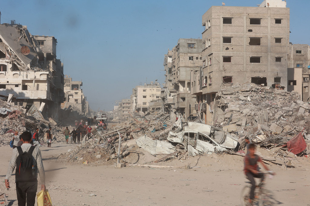 Gazans walk through the rubble of destroyed buildings.
