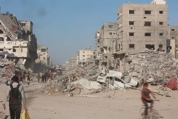 Gazans walk through the rubble of destroyed buildings.