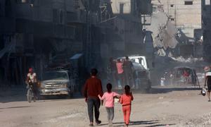 A man and two children walk through the devastated streets of Gaza.
