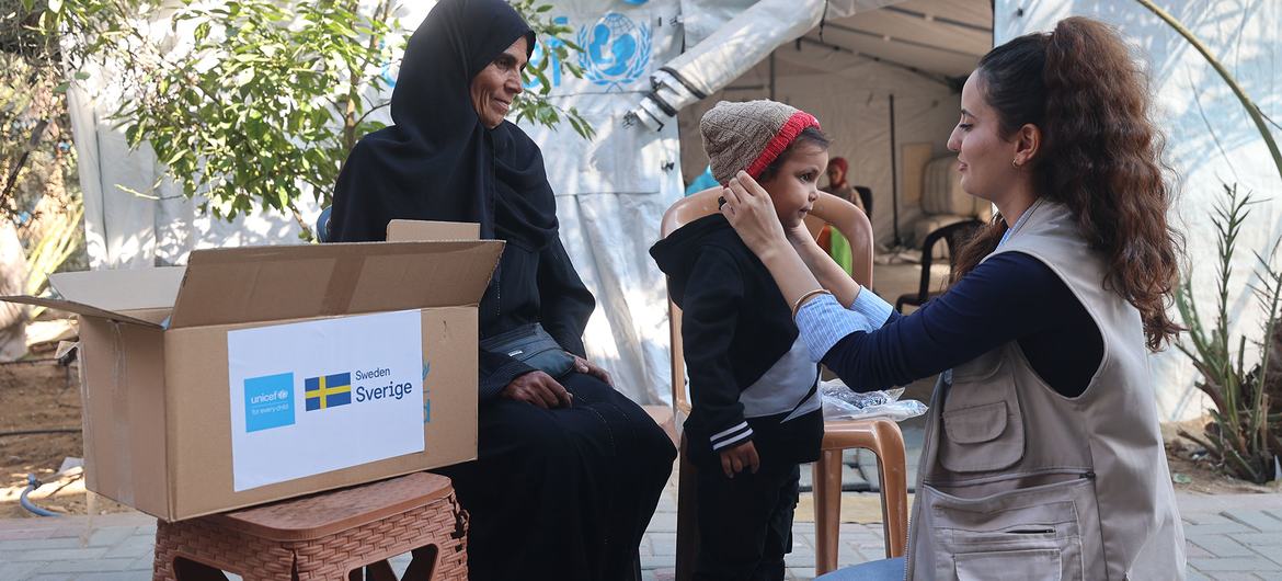 Un trabajador de UNICEF distribuye kits de ropa de invierno a un niño en la Franja de Gaza.