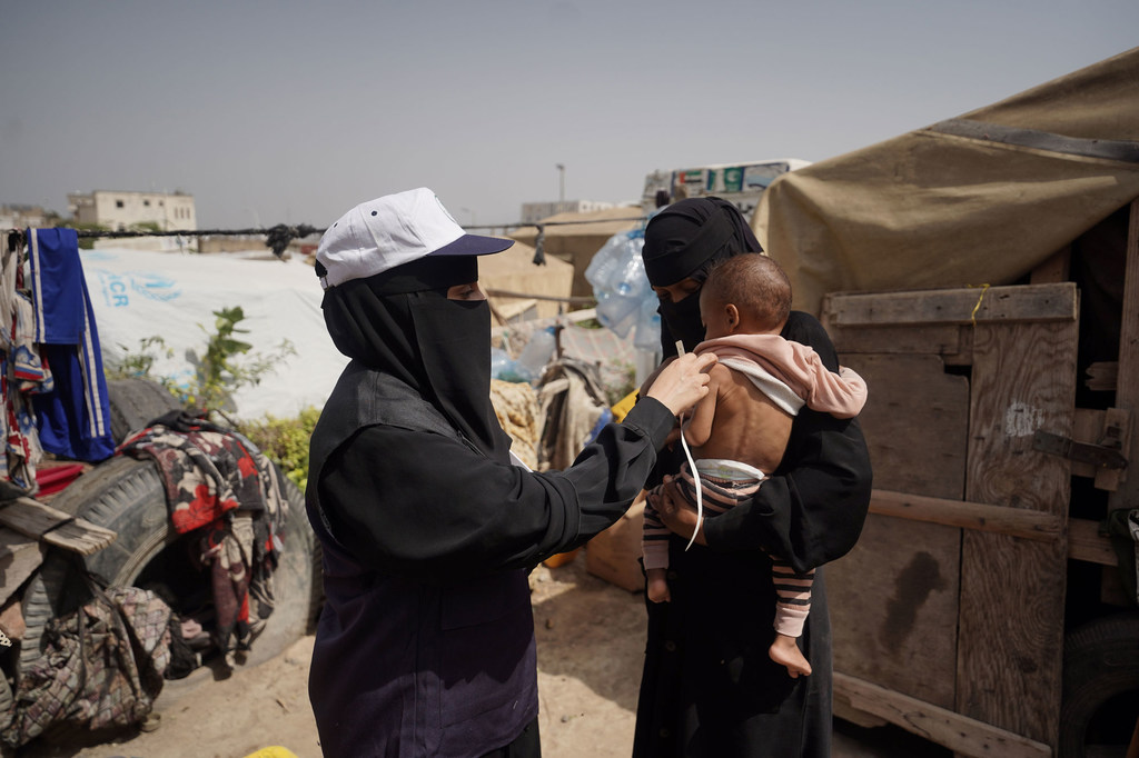 Un bébé est examiné par un bénévole dans un camp à Qataba, dans le sud-ouest du Yémen.