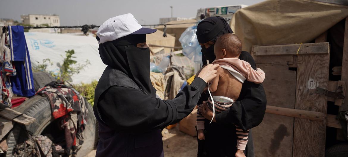 在也门西南部卡塔巴的一个营地里，一名卫生保健志愿者正在为一名婴儿进行检查。