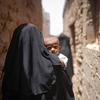 Una madre camina con su hijo en brazos por el barrio Al Adani de Al Hawtah, Gobernación de Lahj, Yemen.