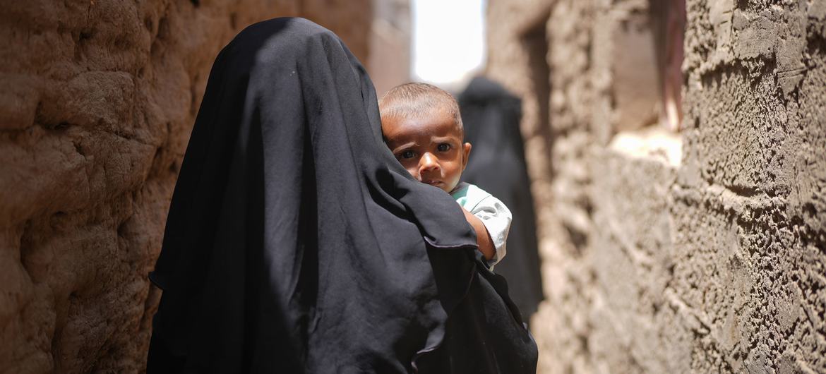 Una madre camina con su hijo en brazos por el barrio Al Adani de Al Hawtah, Gobernación de Lahj, Yemen.