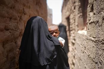 Una madre camina con su hijo en brazos por el barrio Al Adani de Al Hawtah, Gobernación de Lahj, Yemen.