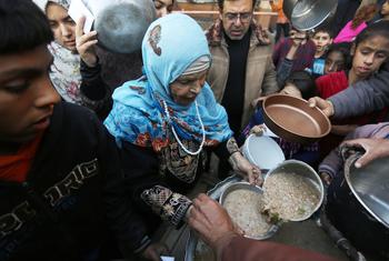 在加沙一个由学校改建的避难所附近的分发点，流离失所的巴勒斯坦人在领取食物。