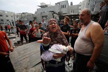Familias palestinas frente a edificios dañados y destruidos por los bombardeos israelíes a Gaza.