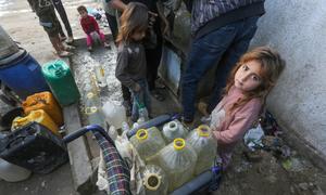 A young girl waits to fill water containers in Gaza.