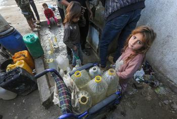 Una niña espera para llenar contenedores de agua en Gaza.