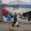 A young boy passes by a shelter on the way to collect water.