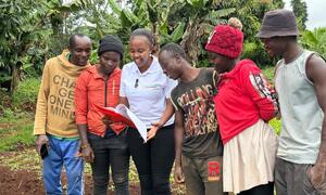 Maryanne Gichanga, a Kenyan agricultural entrepreneur, leads a group of farmers in a field, reviewing data from IoT sensors and satellite imagery to improve crop health and weather insights.
